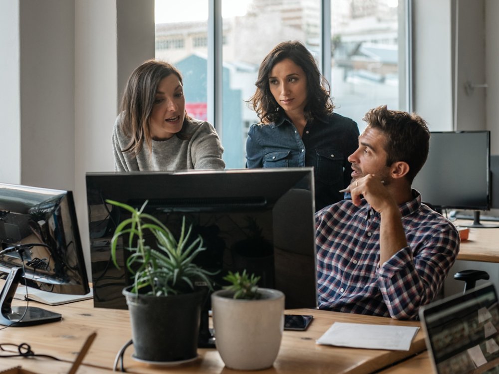 Diverse group of young designers working on a computer together