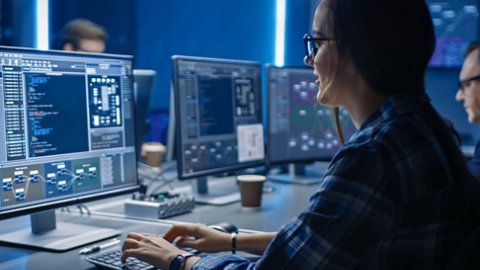 Smart Female IT Programer Working on Desktop Computer in Data Center System Control Room. Team of Young Professionals Doing Code Programming