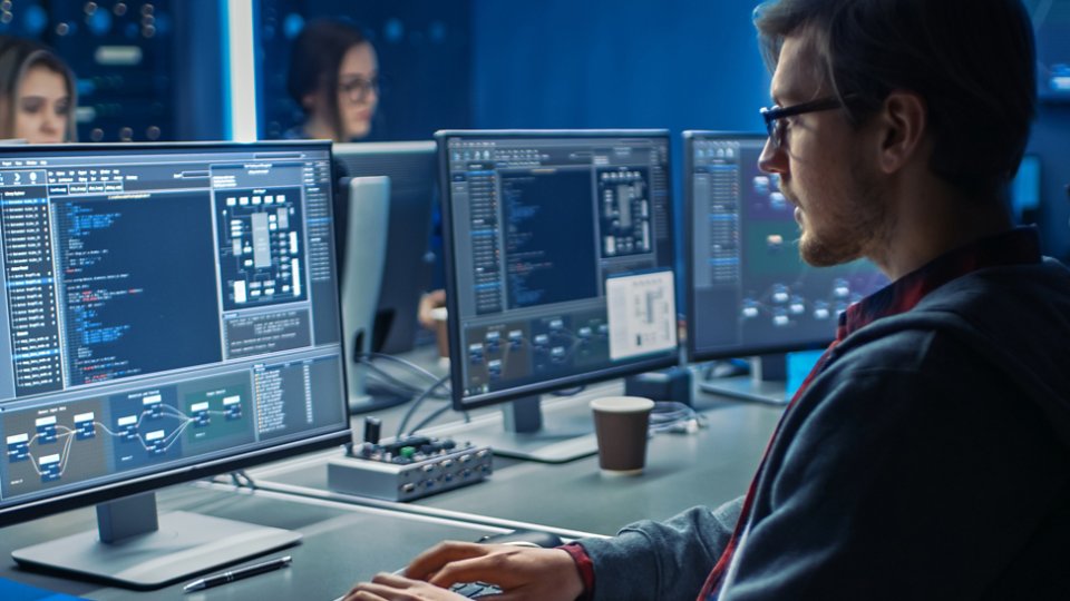 Smart Male IT Programer Working on Desktop Green Mock-up Screen Computer in Data Center System Control Room. Team of Young Professionals Programming Sophisticated Code