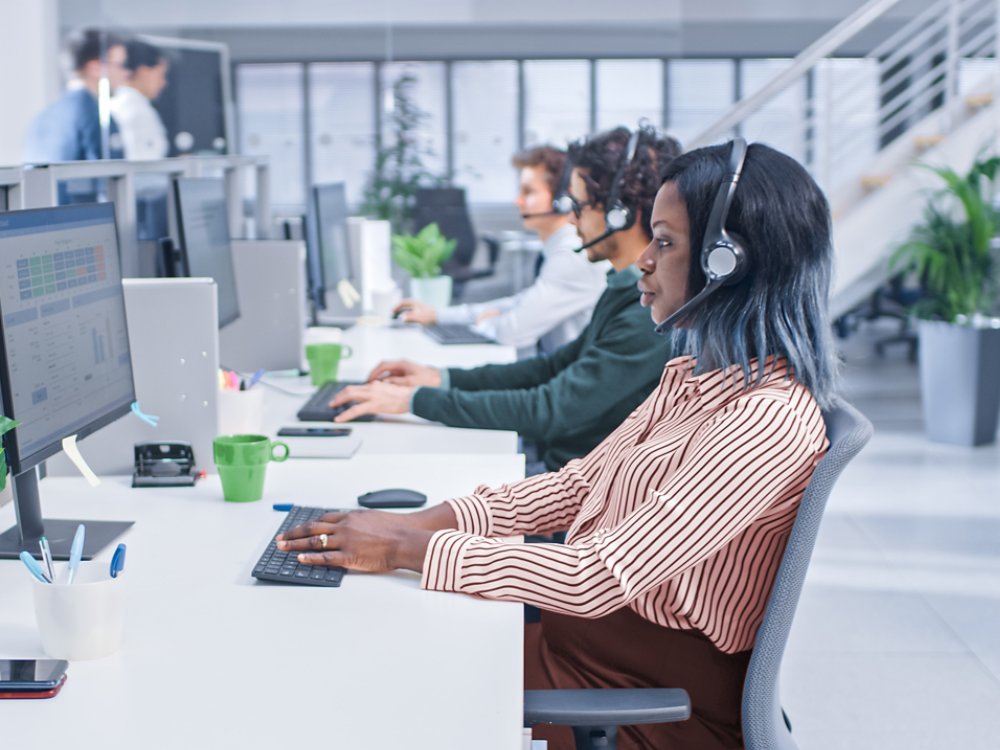 Team of Diverse Multicultural Customer Service Operators Working at a Busy Modern Call Center with Specialists Wearing Headsets and Actively Taking Calls.