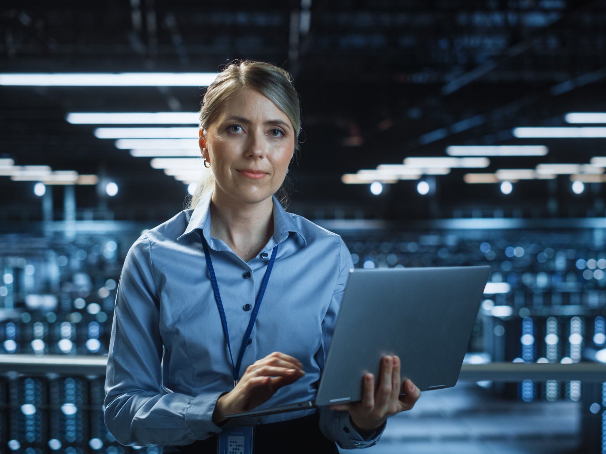 Woman working on laptop in a large data center