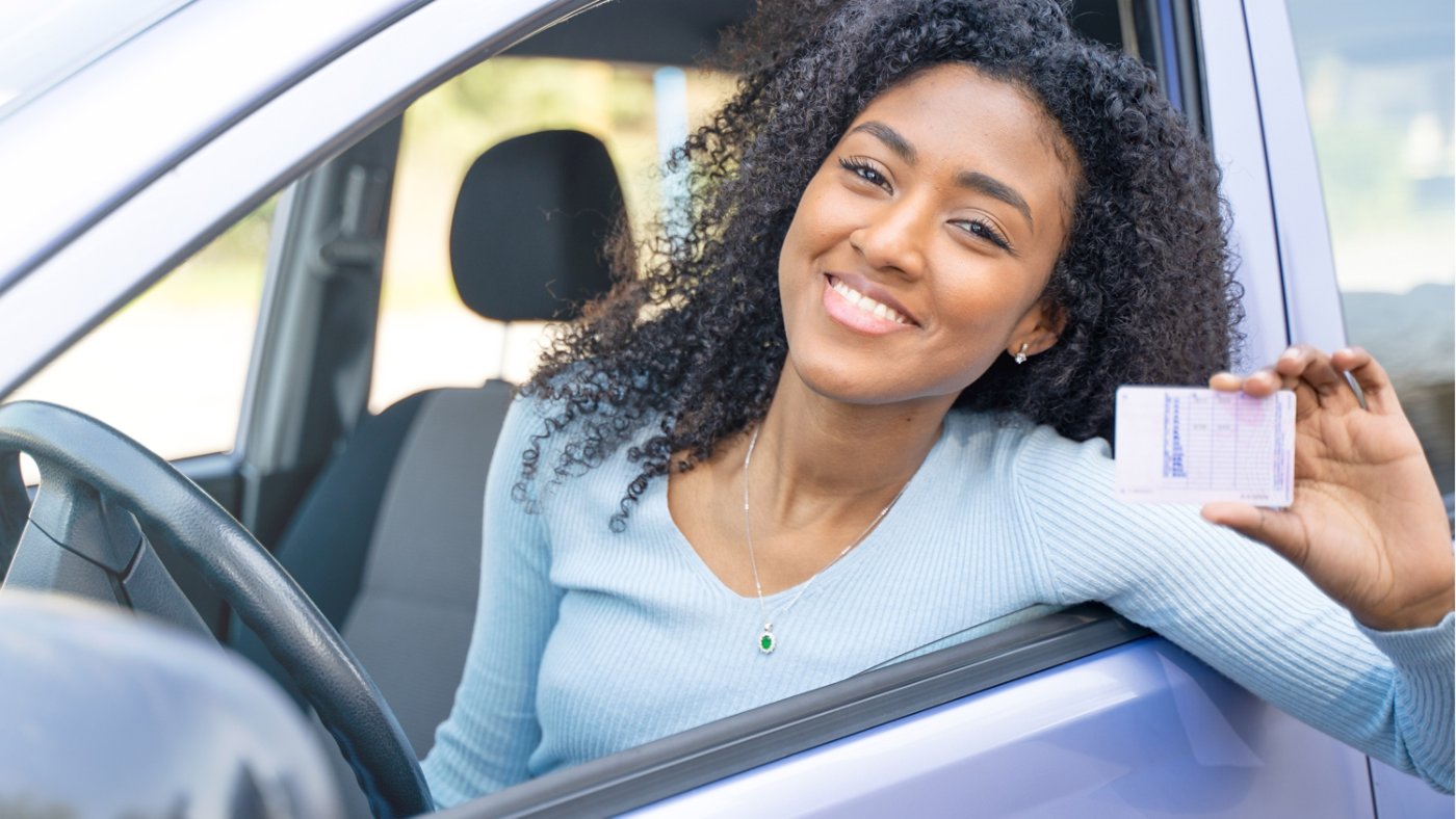 A young black smiling woman show her drive license
