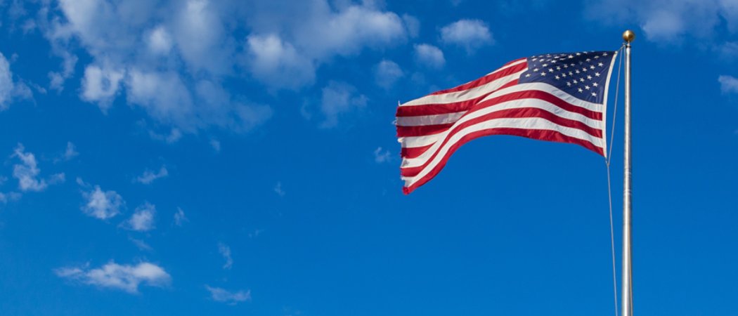 American flag - star and stripes floating over a cloudy blue sky