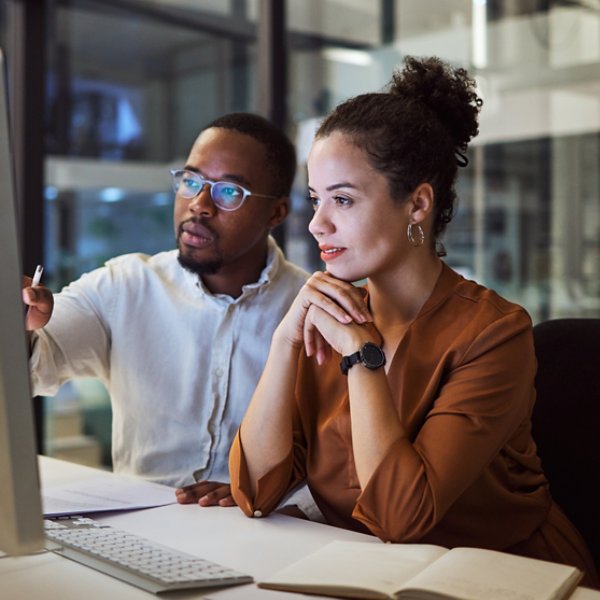 Business training, night planning and employees talking about corporate proposal on internet in dark office at night. African workers working on partnership on the web with computer during overtime.