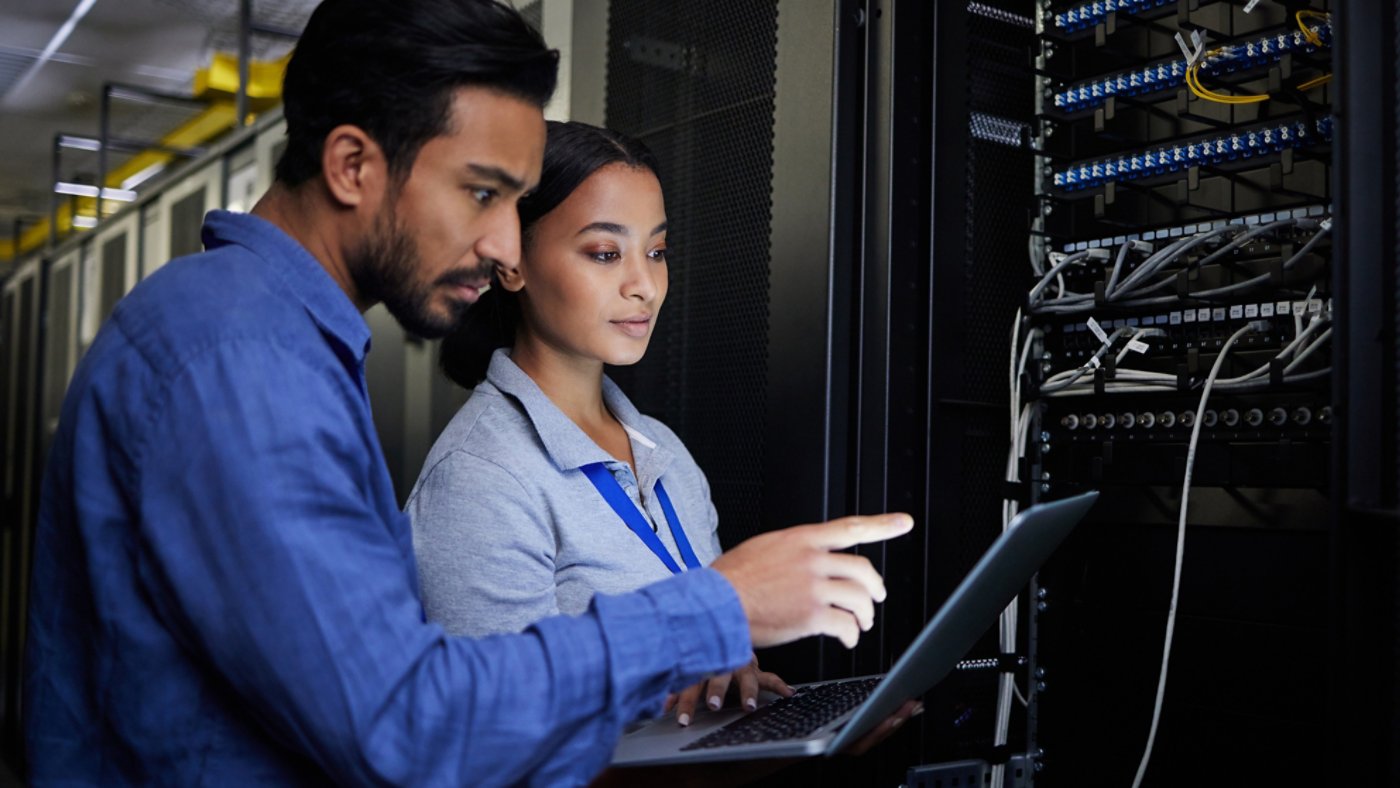two people, a man and a woman, working in a data center