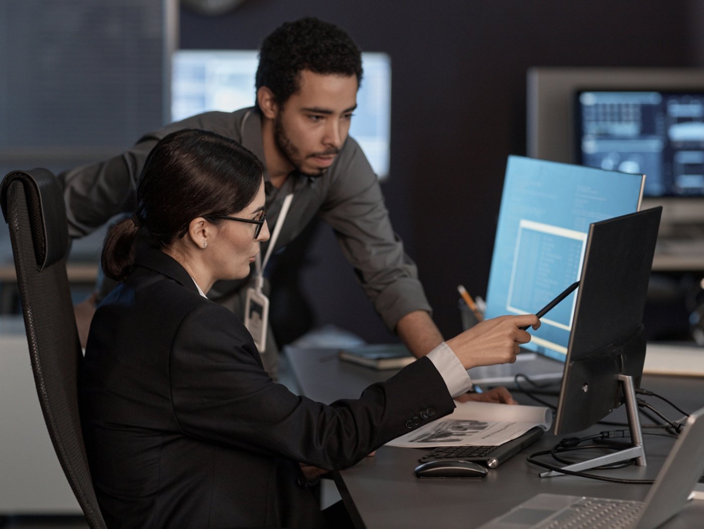 Two people pointing at computer screen while working in IT company