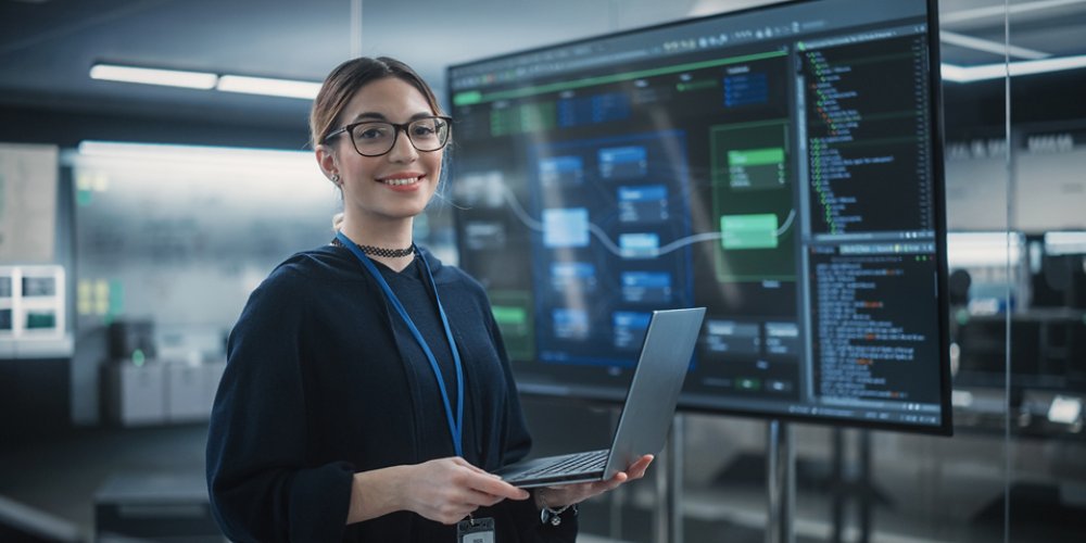 Female Wearing Glasses, Using Laptop Computer, Looking at Camera and Smiling
