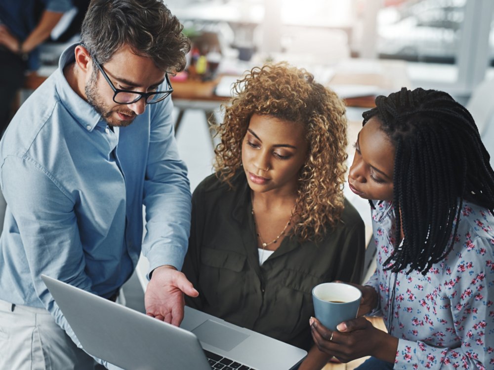 Business growth is a team task. a group of colleagues using a laptop together in a modern office.