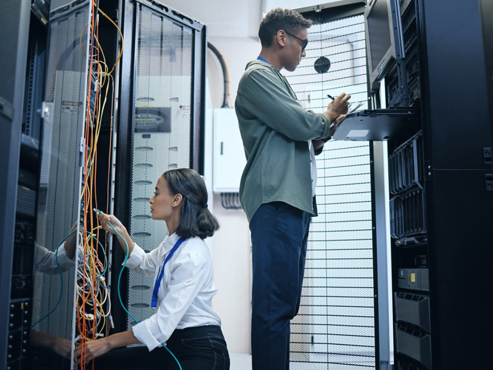 Server room, engineer and IT team with a tablet for programming, cybersecurity or cable maintenance. Man and woman technician together in datacenter for network, software or system upgrade with tech