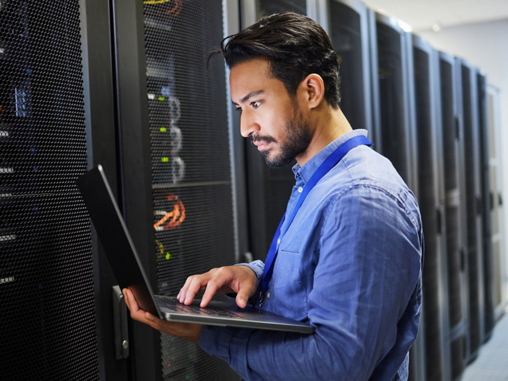 Programming, data center and a man with a laptop for maintenance, cyber security and internet check. Coding, email and an Asian programmer typing on a computer for network or server analytics