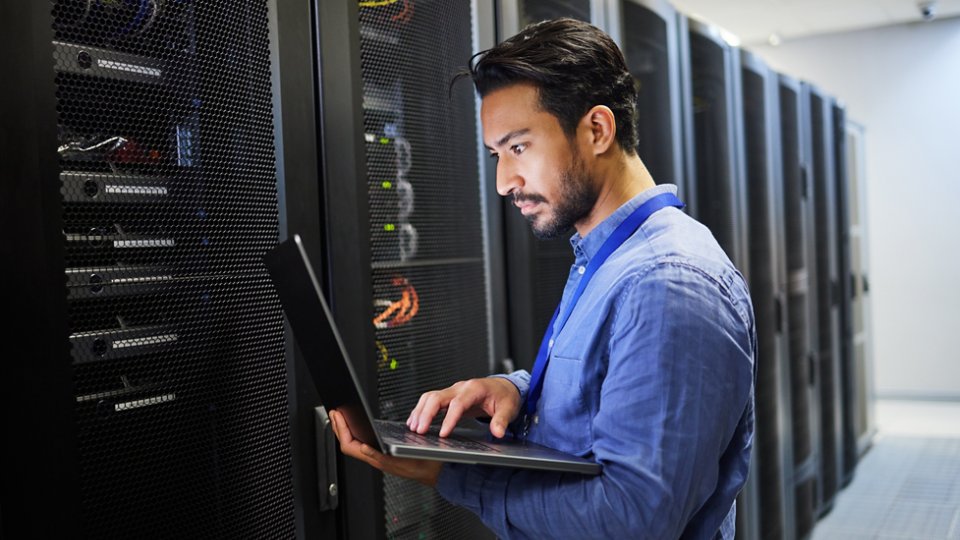 Programming, data center and a man with a laptop for maintenance, cyber security and internet check. Coding, email and an Asian programmer typing on a computer for network or server analytics