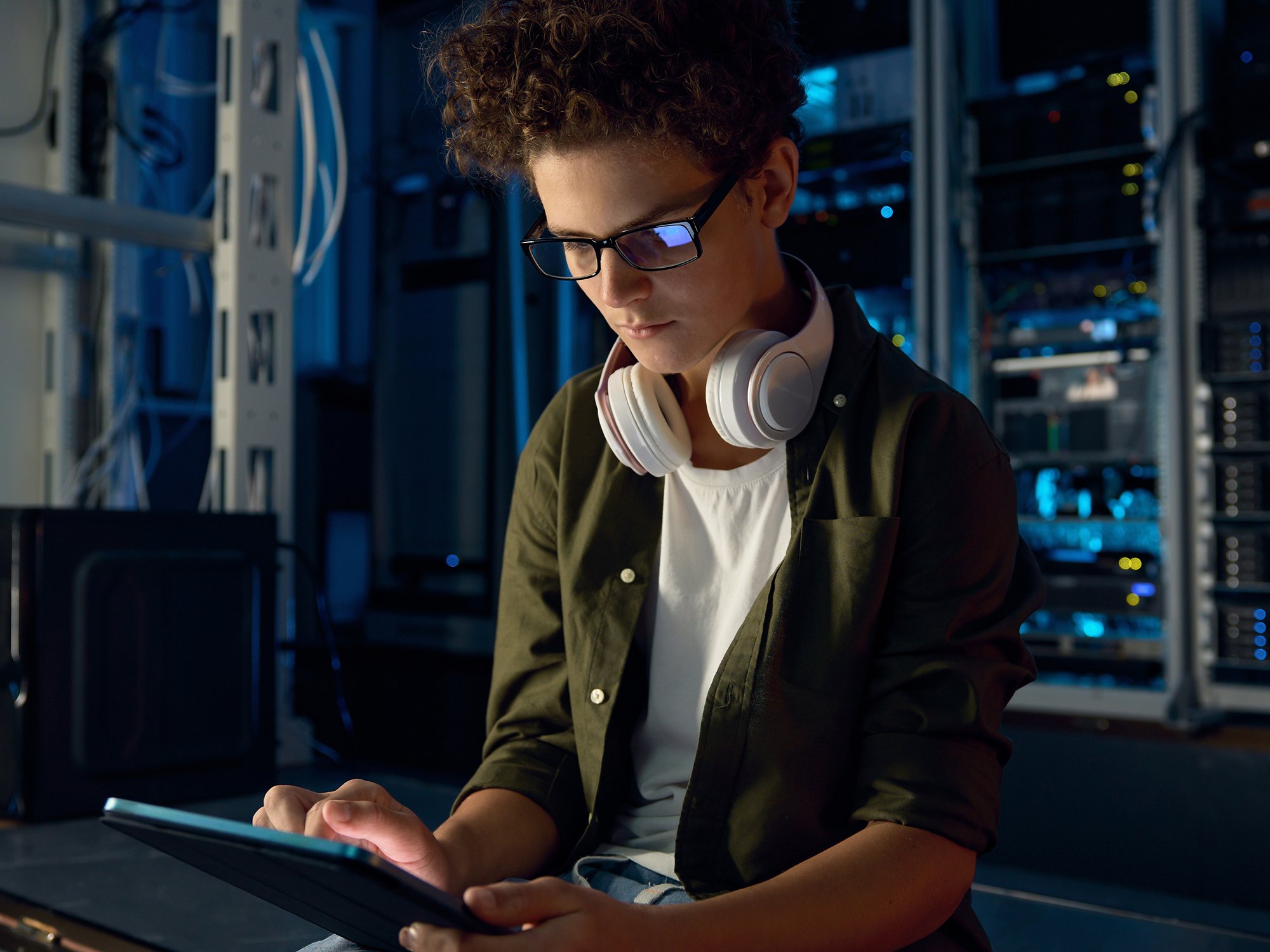 Teenager guy IT technician working on tablet inside server room