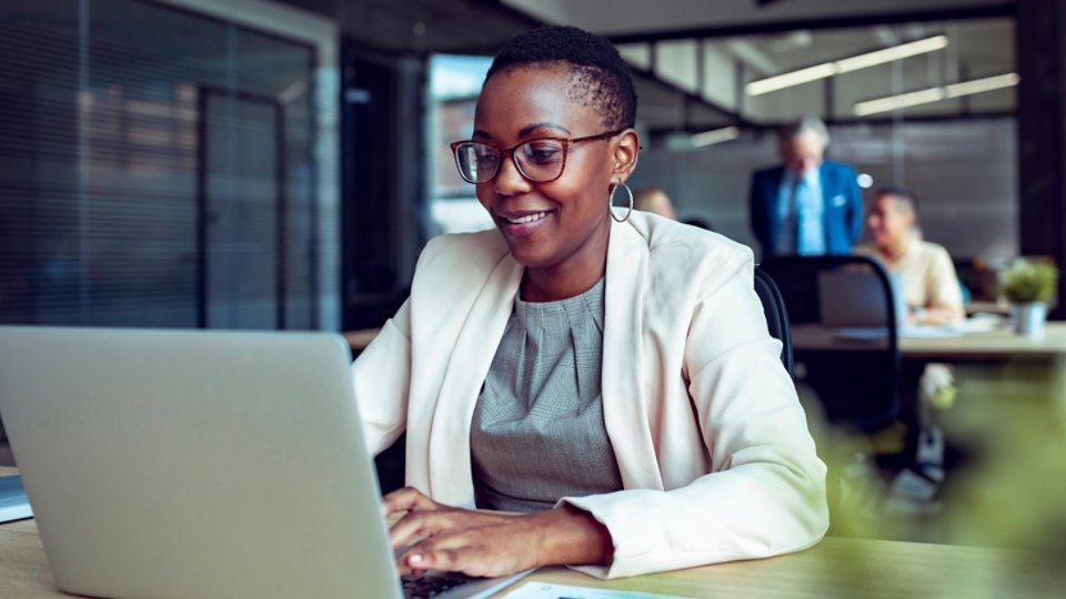 Smiling businesswoman working on laptop in office