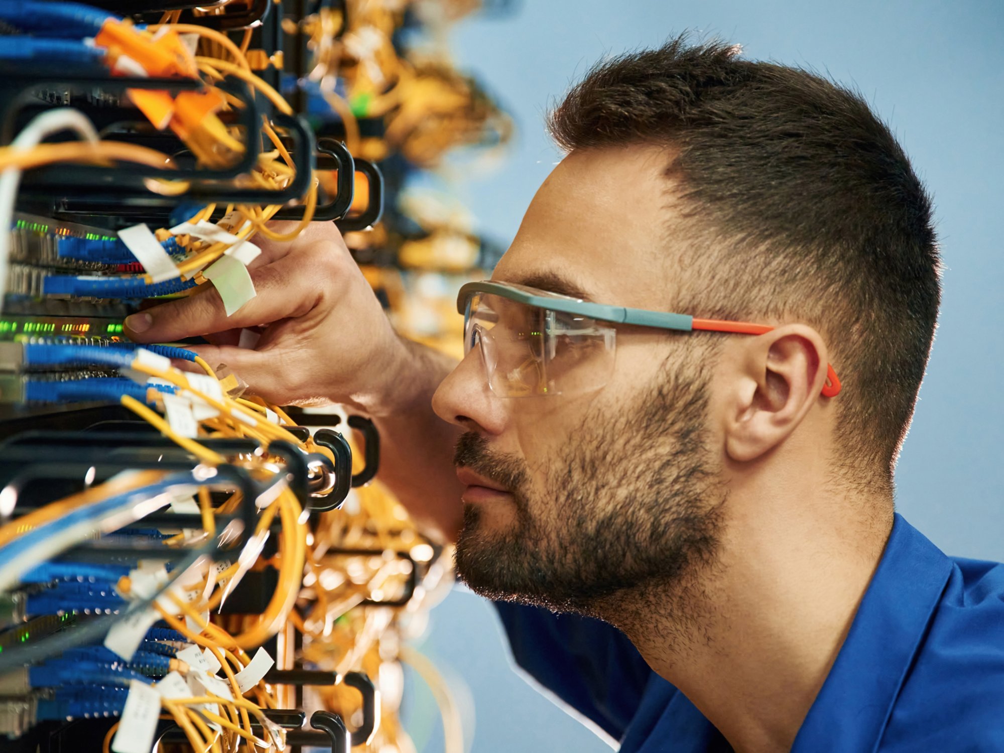 Looking extremely close at cables. Young man is working with internet equipment and wires in server room