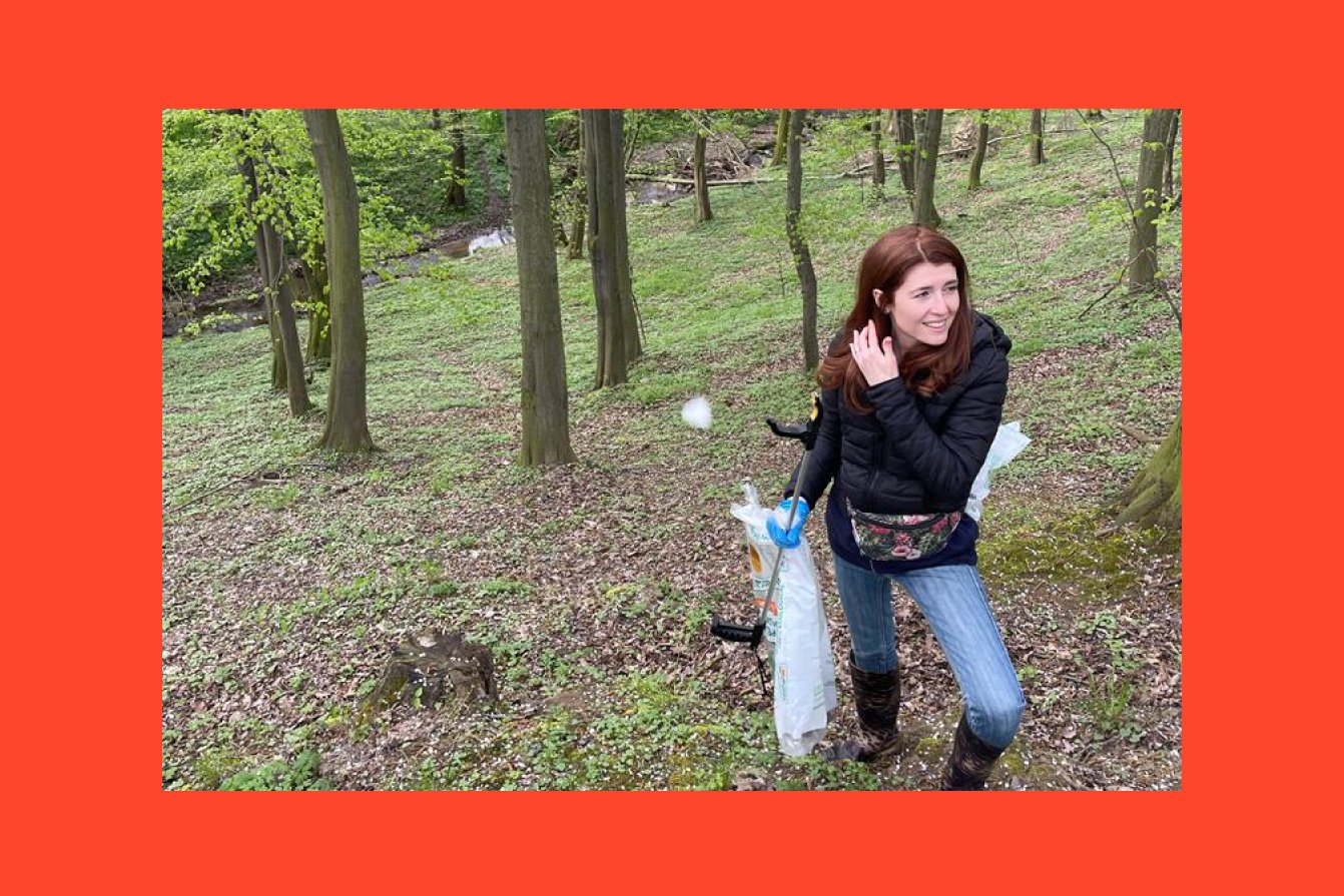A young woman is collecting garbage in the forest.