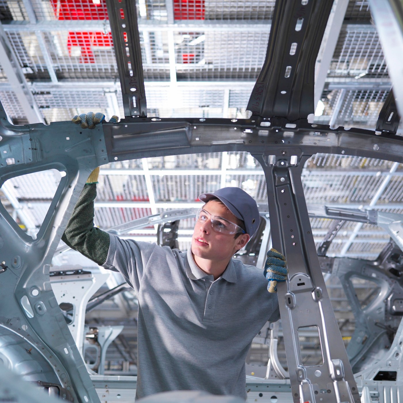 Worker inspecting car at automotive plant.