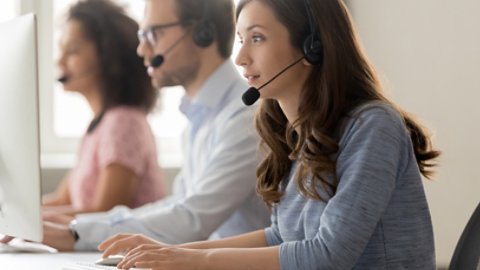 Young woman call center agent in headset consulting online client