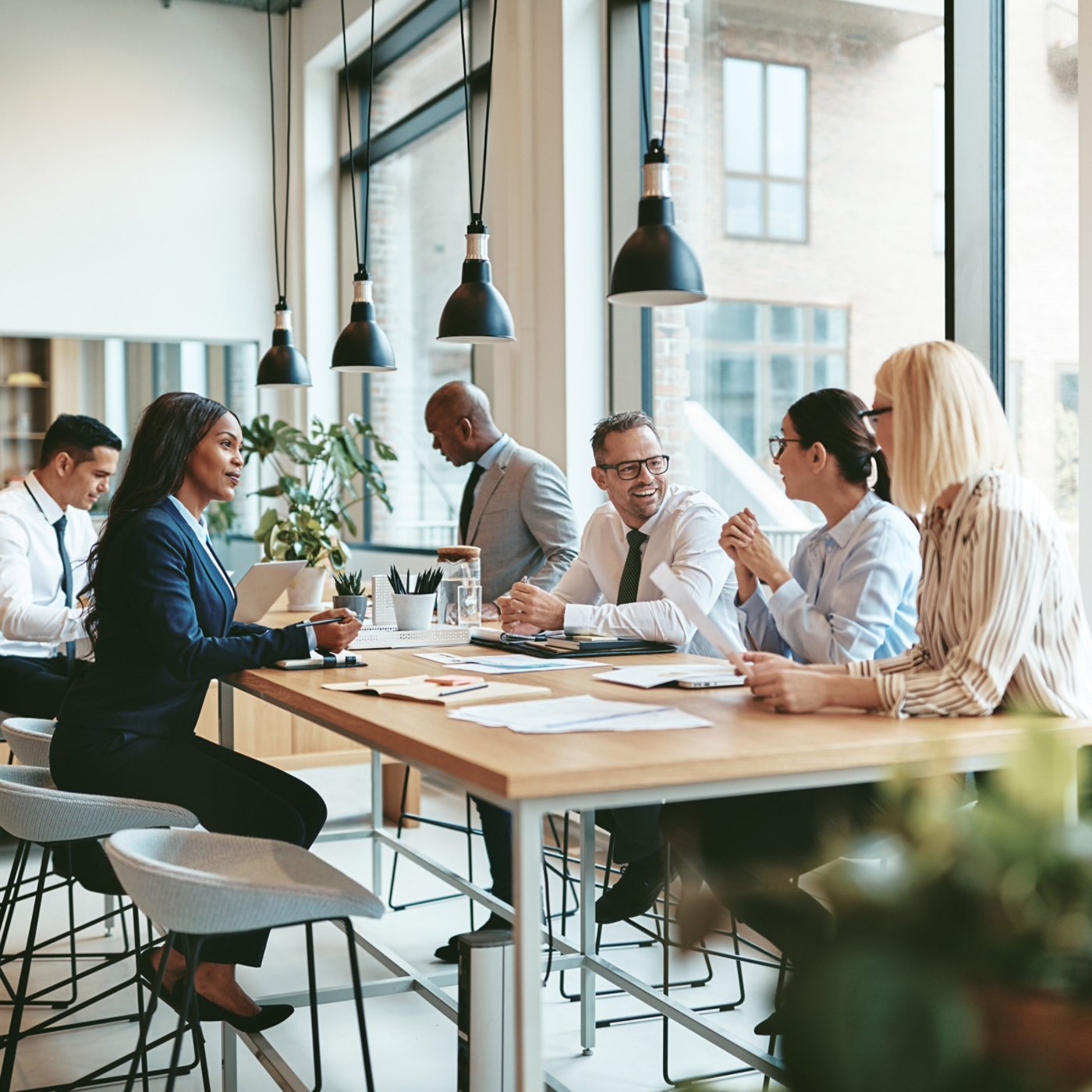 Smiling group of diverse businesspeople discussing paperwork together while having a meeting around a table in a modern office