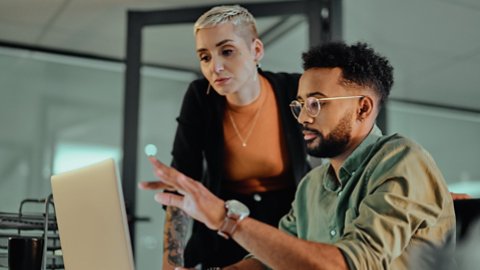Shot of two young designers working together on a laptop in an office at night