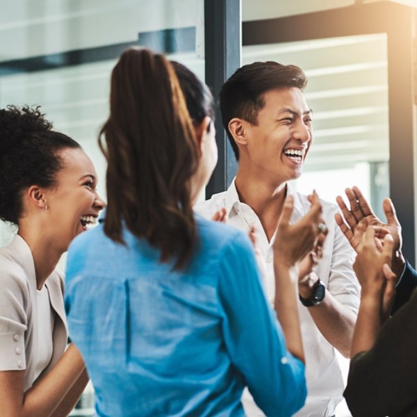 Shot of a group of young businesspeople standing together and clapping in a modern office