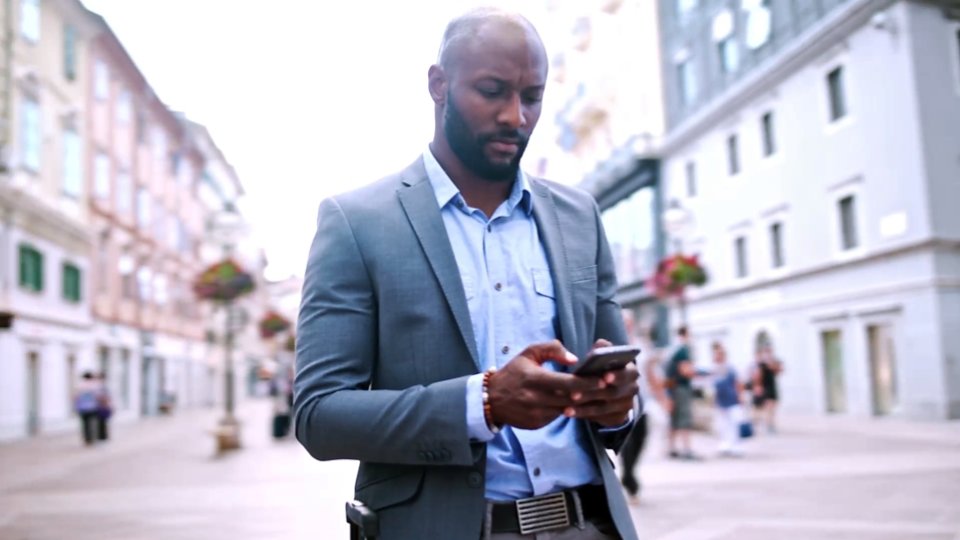 A still image focused on a man looking at his cell phone depicting improved citizen experiences and outcomes