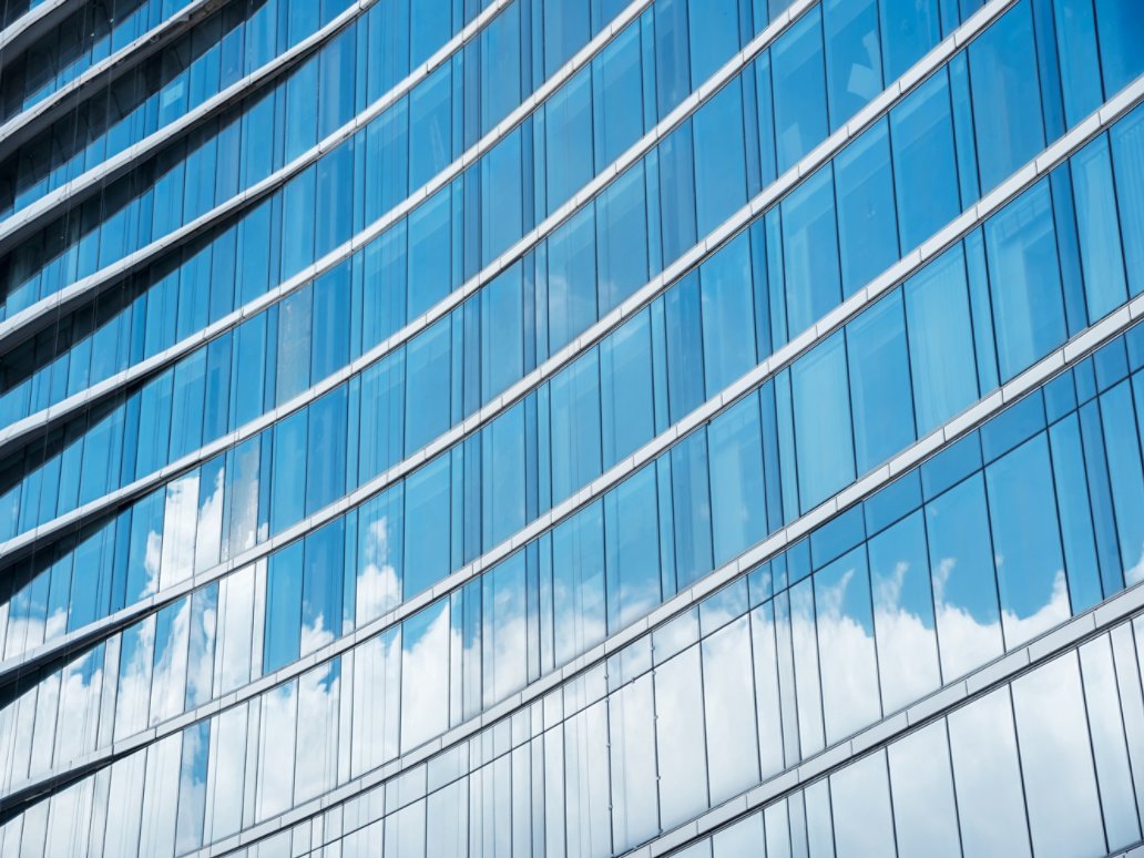 Pattern of blue glasses in high building with shadow of cloud. Abstract modern building background.
