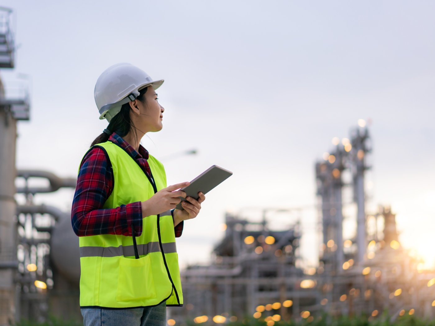 Asian woman petrochemical engineer working with digital tablet Inside oil and gas refinery plant industry factory for inspector safety quality control.
