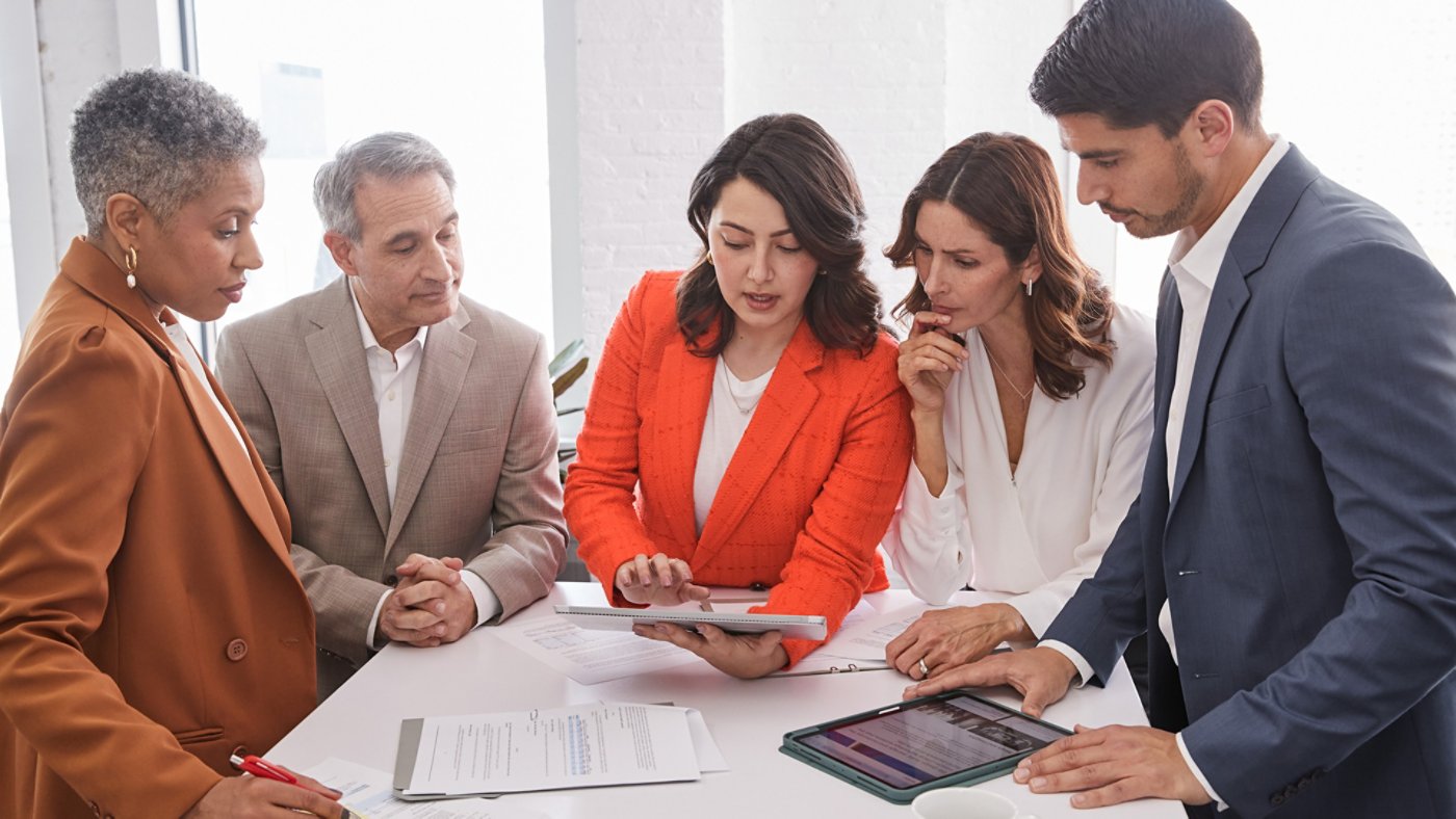 Colleagues meeting around a table viewing a tablet