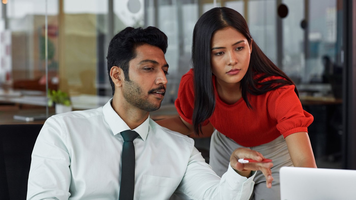 A businessman and a businesswoman looking at the laptop and discussing 16X9