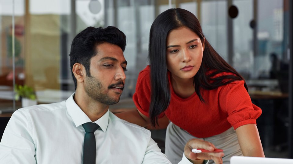 A businessman and a businesswoman looking at the laptop and discussing 4X3