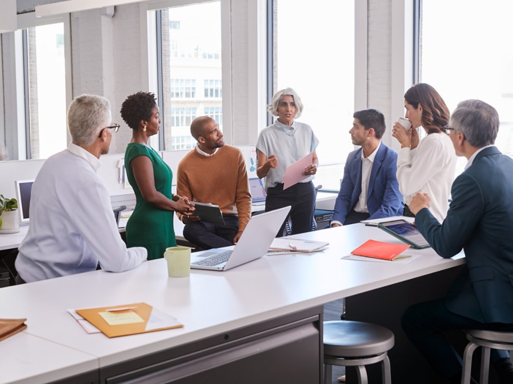 Group of multi ethnic business people standing and discussing business and reports 4X3