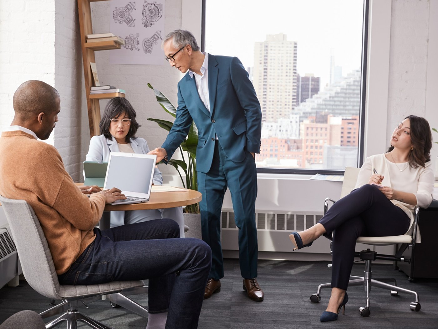 Four people working on a business project in a windowed office