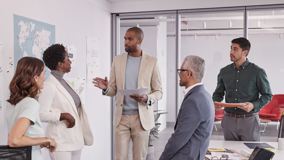 5 multi ethnic business people standing in a meeting room and discussing business operations 4X3