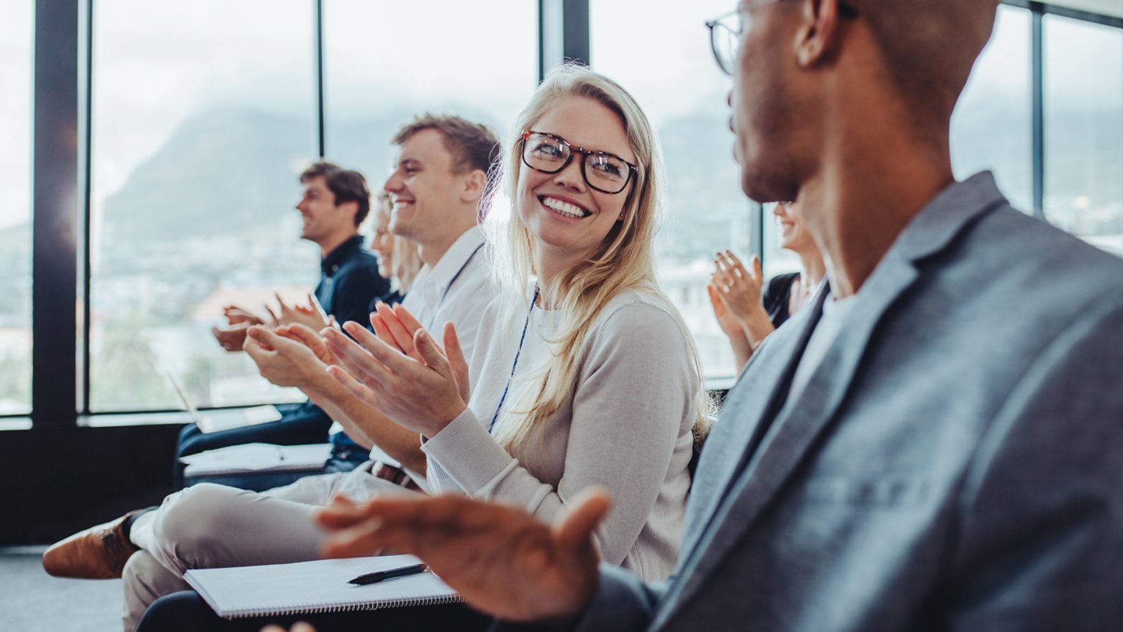 Group of businesspeople applauding speaker after conference presentation. Business men and women sitting in audience clapping hands.