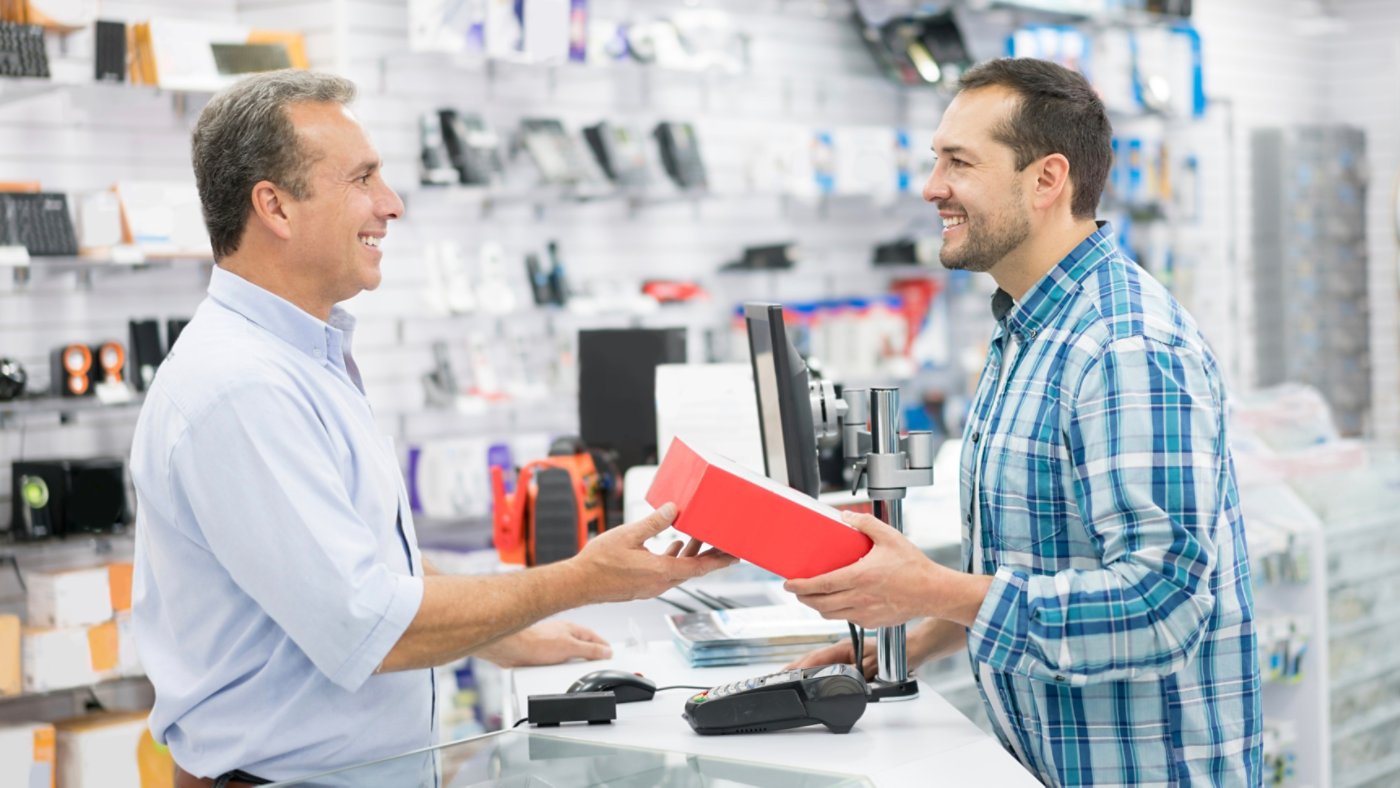 Casual man shopping at a tech store and talking to salesman over the counter