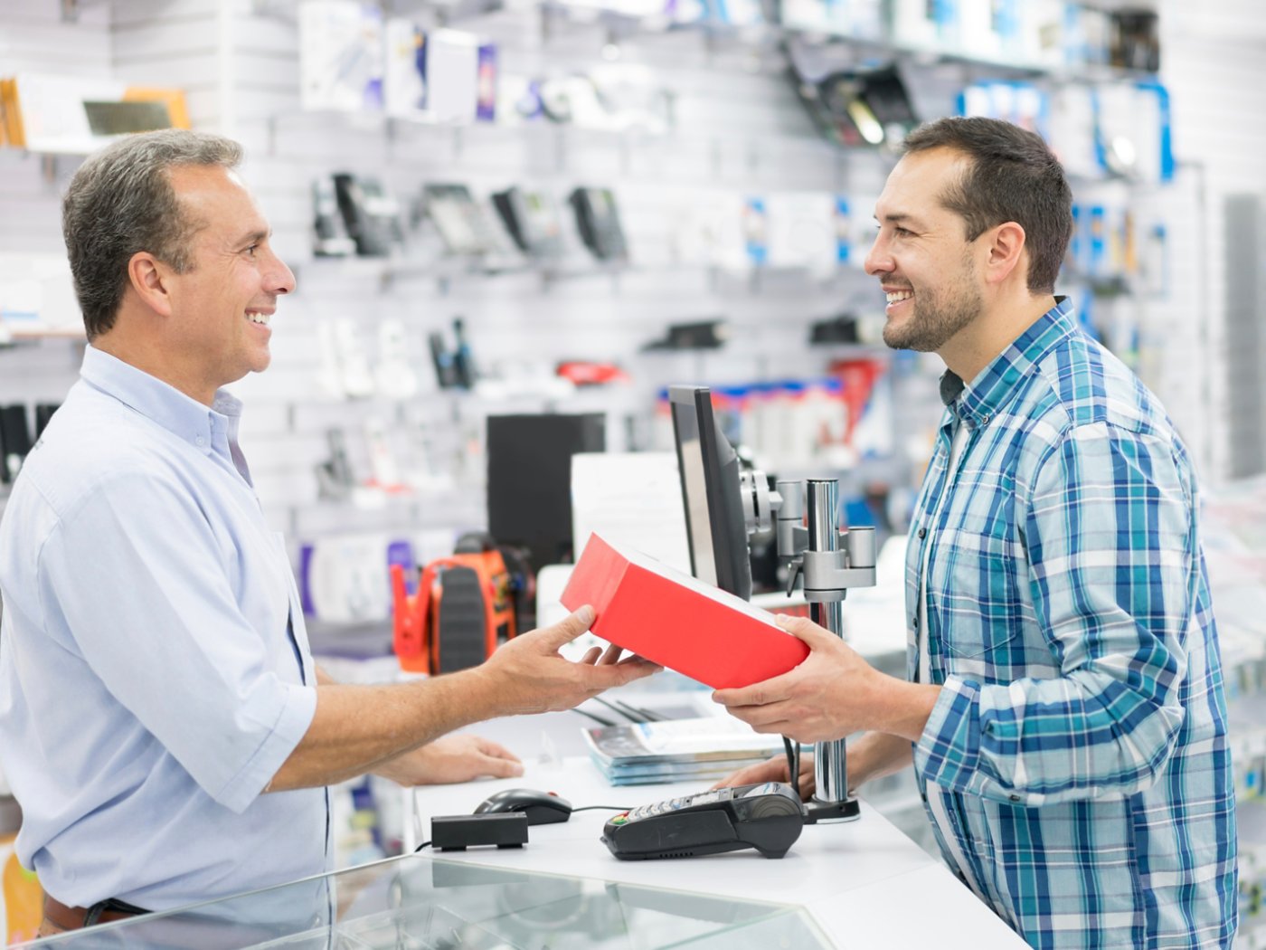 Casual man shopping at a tech store and talking to salesman over the counter