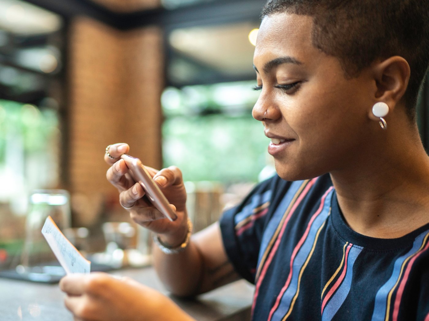 Young woman depositing check by phone in the cafe