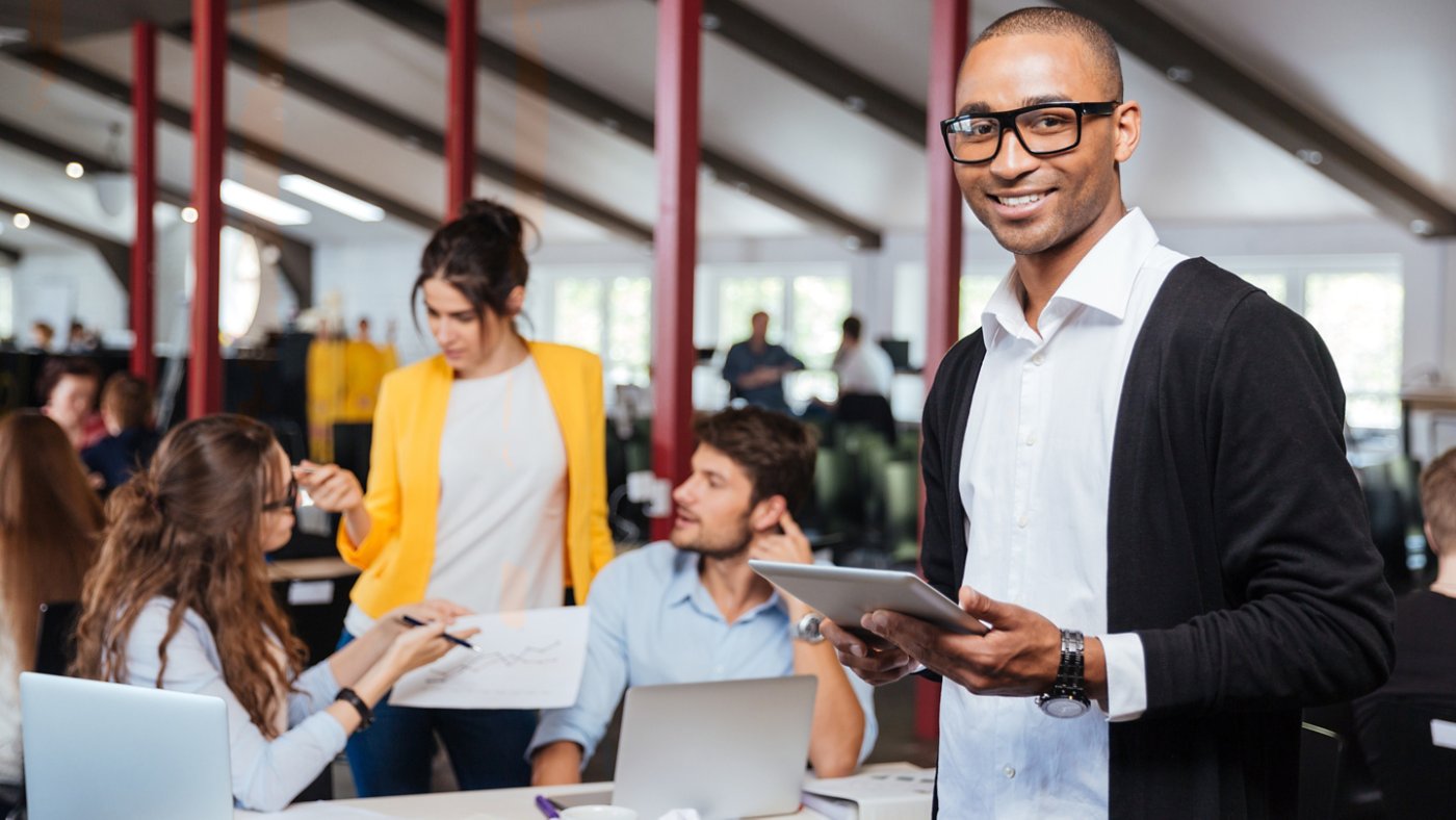 Cheerful african young businessman using tablet in office