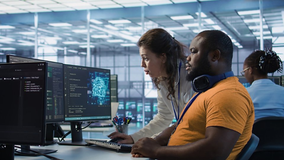 Team leader teaching IT specialist how to while monitor AI supercomputers