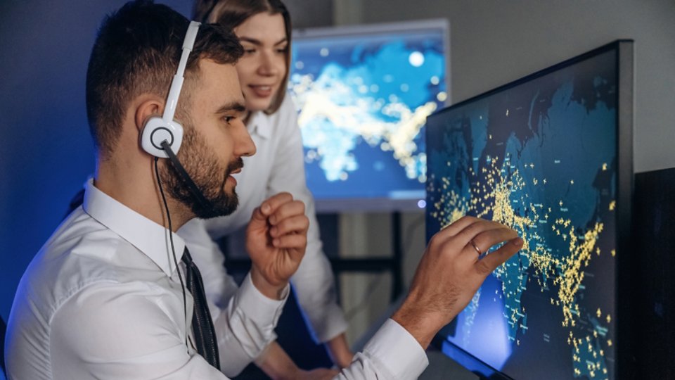 Looking at map together. People are working by computers in airline company