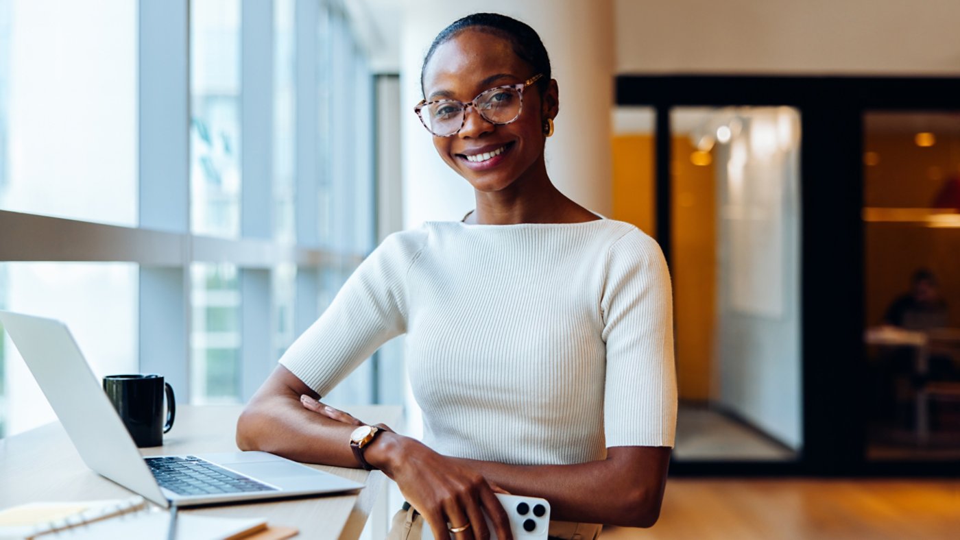 Confident young professional woman with a laptop and notepad in office