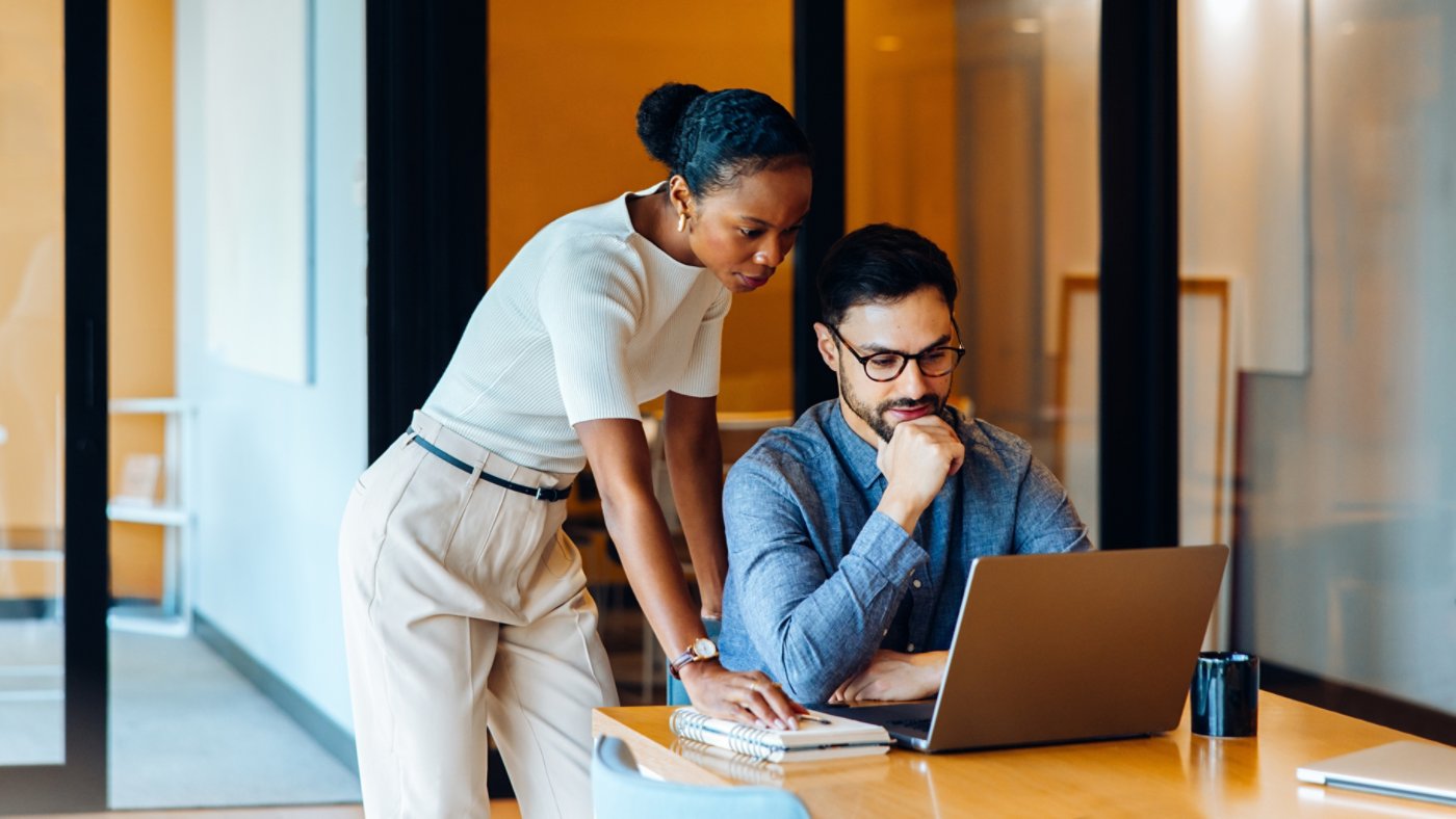 Two professionals analyzing data on a laptop in an office environment