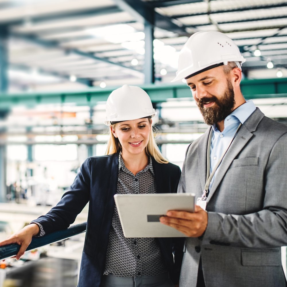 A portrait of an industrial man and woman engineer with tablet in a factory, working.