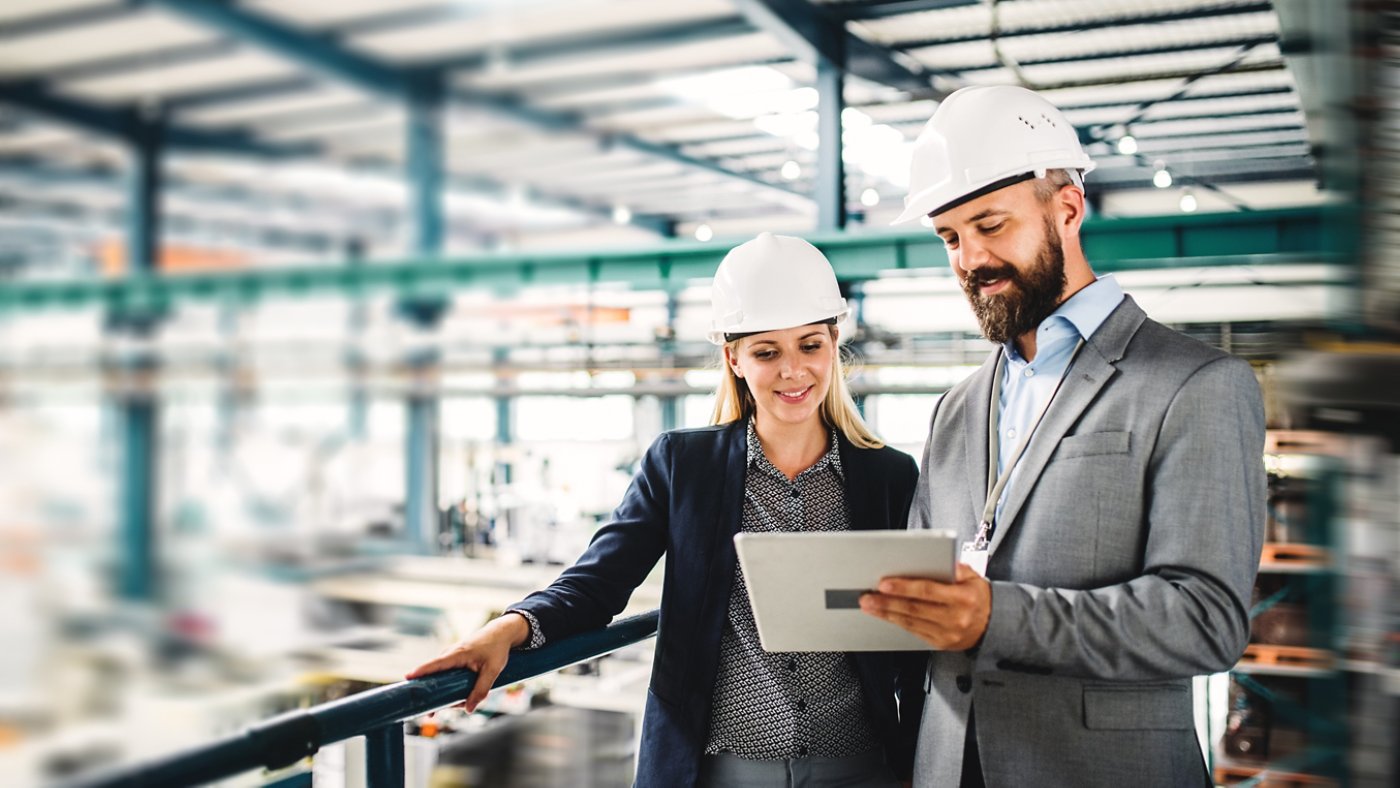 A portrait of an industrial man and woman engineer with tablet in a factory, working.