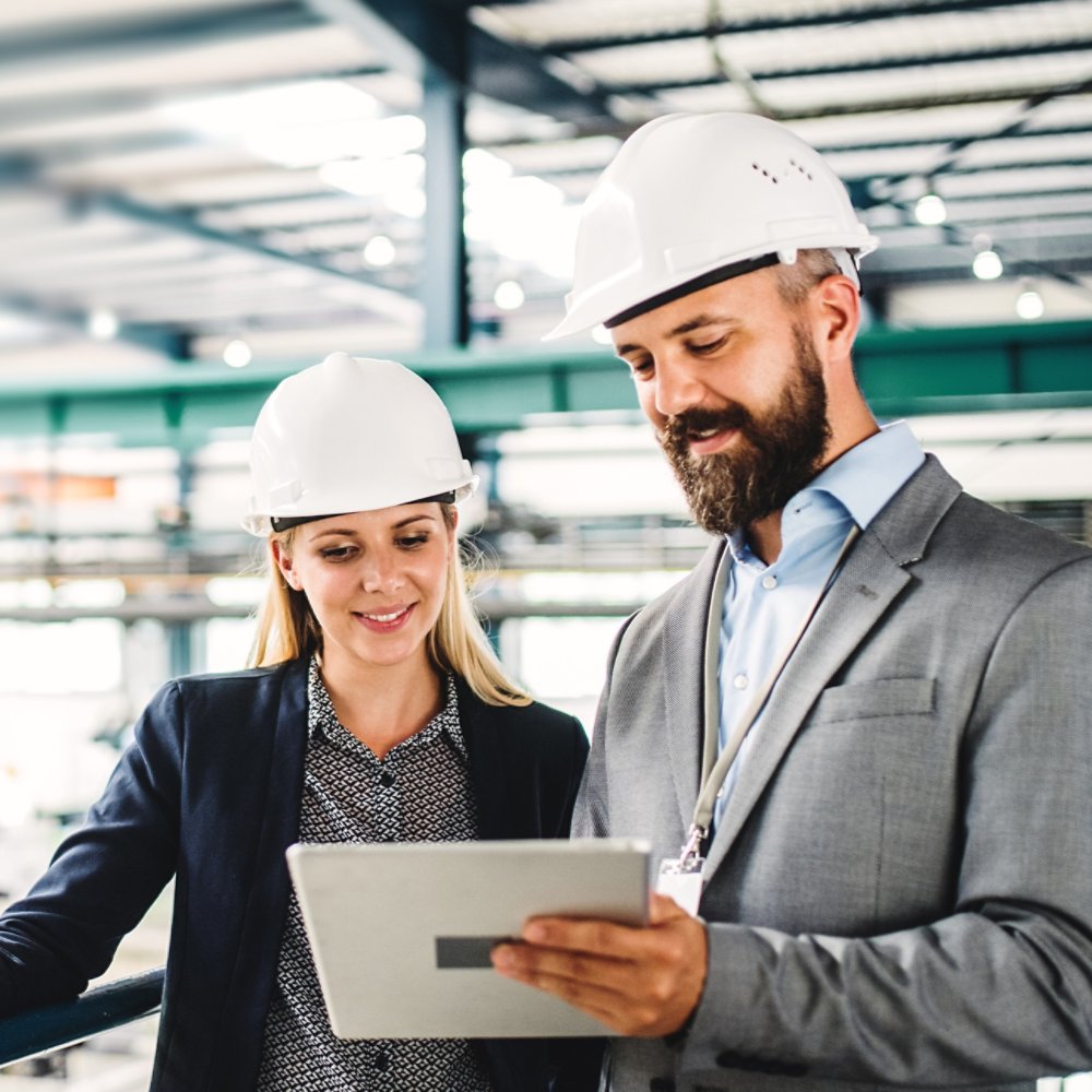 A portrait of an industrial man and woman engineer with tablet in a factory, working.