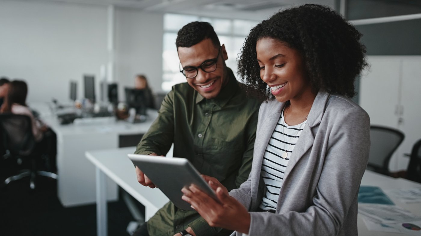Smiling young african american professional businessman and businesswoman together working online with a digital tablet in office