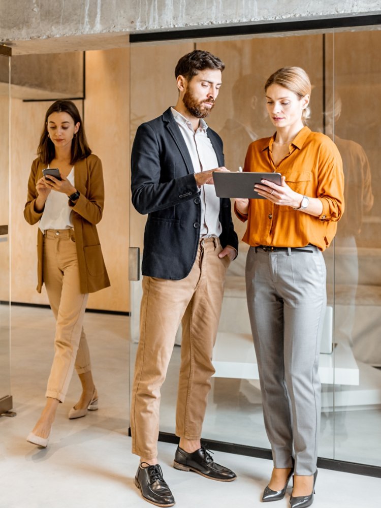 Colleagues meeting in the hallway, solving some working moments with digital tablet. Work in marketing agency or design studio concept
