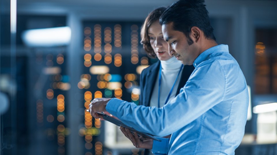 Man and woman looking at a computer tablet, in. data center