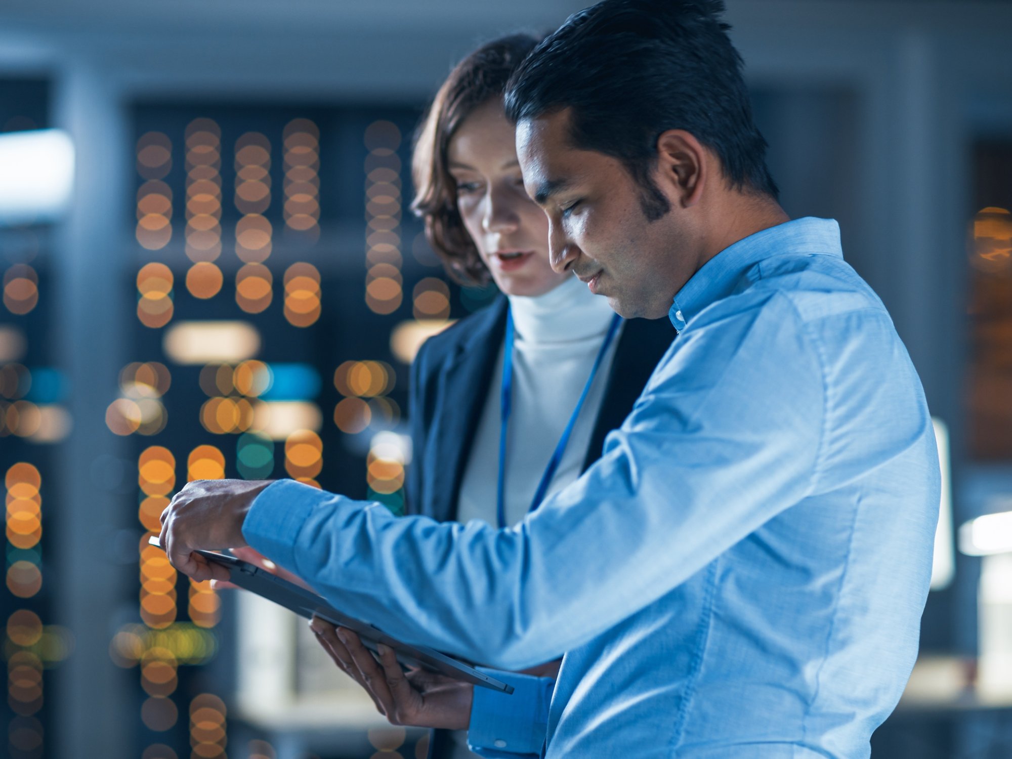 Man and woman looking at a computer tablet, in. data center