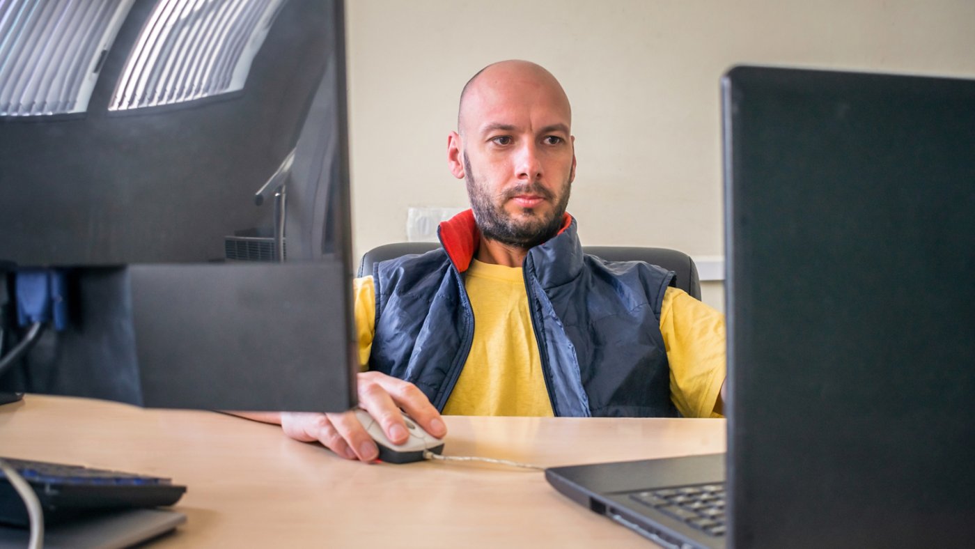 Man focused on working on two computer screens 16x9